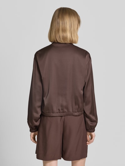 Frauenmodel trägt Blouson mit Viskose-Anteil und Reißverschluss von comma in Braun, Satin-Oberfläche, elastische Abschlüsse, Ganzkörperansicht Rückansicht.