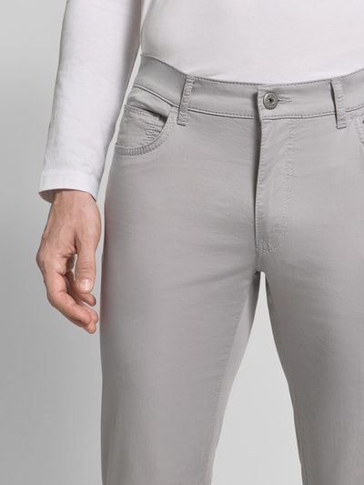 Männermodel trägt Regular Fit Stoffhose mit Lyocell-Anteil Modell 'Cadiz' von Brax in Hellgrau, 5-Pocket-Design, Nahaufnahme Oberkörper. Elastischer Baumwoll-Mix, Bundweite 107 cm, Innenbeinlänge 81 cm, Knopf- und Reißverschluss.
