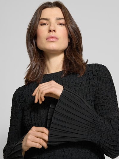 Frauenmodel trägt Regular Fit Langarmbluse in Crinkle-Optik Modell 'BOPPAR' von BOSS, schwarze Unifarbe, plissierte Ärmel, Nahaufnahme Oberkörper.