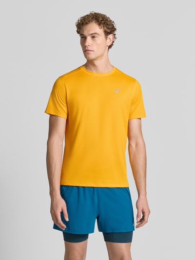 Męski model nosi t-shirt z prostym krojem od ASICS TIGER Model 'CORE' z nadrukiem z logo, okrągły dekolt, kolor żółty, Długość tyłu w rozmiarze M: 72 cm, Ganzkörperansicht von vorne.