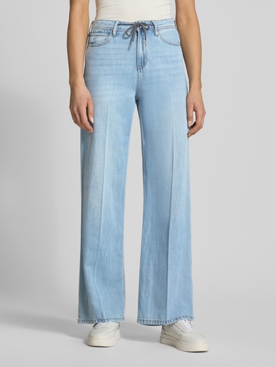 Frauenmodel trägt Wide Leg Jeans aus Lyocell-Baumwoll-Mix Modell 'SURI' von s.Oliver RED LABEL, Denim-Optik, hellblau, 5-Pocket-Design, Label-Patch, Tunnelzug, Knopf und verdeckter Reißverschluss, Mid Waist Passform, strukturierte Oberfläche, Ganzkörperansicht von vorne.