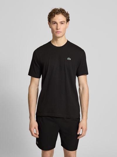 Männermodel trägt Regular Fit T-Shirt aus Baumwoll-Mix von Lacoste Sport, unifarben schwarz mit Logo, Rundhals, kurzarm, Ganzkörperansicht von vorne.