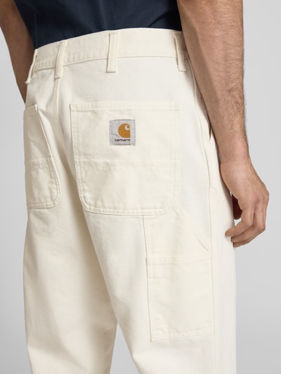 Männermodel trägt Hose mit Eingrifftaschen Modell 'Dearbor' von Carhartt Work In Progress in Creme, Reine Baumwolle, Relaxed-Fit, Detailaufnahme Rückansicht, Bundweite 42 cm, Innenbeinlänge 76 cm.