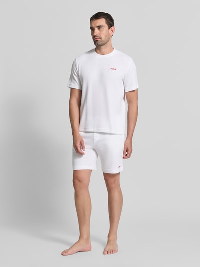 Männermodel trägt weiße Regular Fit Sweatshorts aus Baumwoll-Mix Modell 'AUSTIN' von HUGO, glatte Textur, Ganzkörperansicht von vorne, Herren Sweatshorts von HUGO
