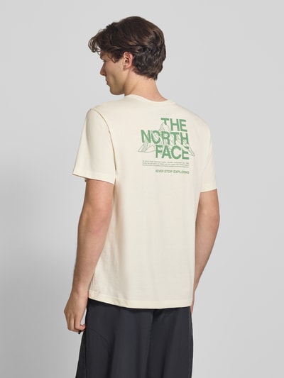 Männermodel trägt T-Shirt mit Logo und Rundhalsausschnitt von The North Face, Beige mit grünem Logo, Baumwoll-Mix, Regular-Fit, Rückenansicht, Rückenlänge bei Größe M 72 cm.