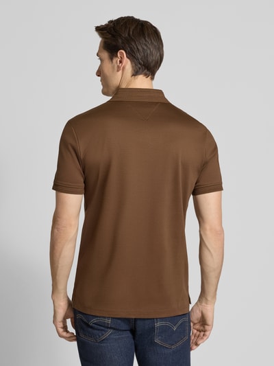 Männermodel trägt Regular Fit Poloshirt aus reiner Baumwolle von Tommy Hilfiger in Braun, unifarben, mit Logo-Detail, Ganzkörperansicht Rückansicht.