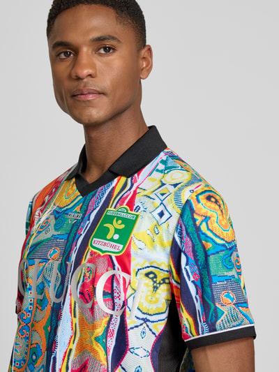 Männermodel trägt Regular Fit T-Shirt mit V-Ausschnitt von COLUCCI, bunt gemustert, Logo-Stitching, Umlegekragen, Nahaufnahme Oberkörper.