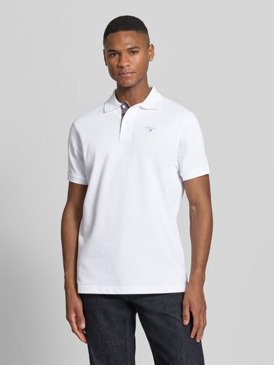 Męski model nosi Regular Fit Poloshirt aus reiner Baumwolle od Barbour, biały kolor, krój regular fit, pikowana bawełna, widok z przodu, ujęcie całej sylwetki.