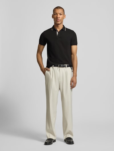 Männermodel trägt Slim Fit Poloshirt aus Baumwolle von Colmar Originals, schwarzes Poloshirt mit Polokragen und Label-Details, Ganzkörperansicht von vorne. Rückenlänge bei Größe M: 66 cm.