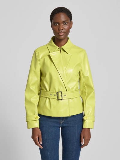 Frauenmodel trägt Jacke mit Gürtel und Ärmelriegeln von Marc Cain in Gelb, Regular Fit, Hakenverschluss, glatte Textur, Ganzkörperansicht von vorne.