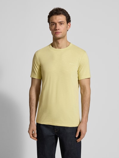 Männermodel trägt Regular Fit T-Shirt aus strukturierter Baumwolle Modell 'TEGOOD' von BOSS Orange in Gelb, unifarben, Kurzarm, Ganzkörperansicht von vorne.