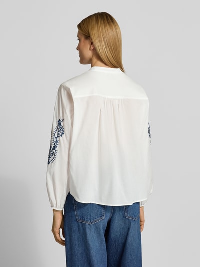 Frauenmodel trägt Regular Fit Bluse mit floralem Stitching Modell 'Februar' von More & More aus reiner Baumwolle, Weiß mit blauen Details, langärmelig, elastische Ärmelabschlüsse, Tunika-Ausschnitt, durchgängige Knopfleiste, Rückenlänge bei Größe 36: 60 cm, Ärmellänge bei Größe 36: 60 cm, Ganzkörperansicht Rückansicht.