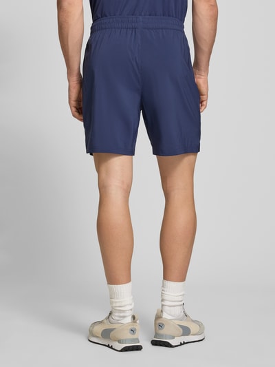 Männermodel trägt Shorts mit Logo und elastischem Bund von PUMA PERFORMANCE in Dunkelblau, glatte Textur, Ganzkörperansicht Rückansicht.