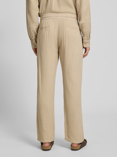Mężczyznamodel nosi Straight Fit Sweatpants in Musselin-Optik od Lindbergh z bawełny, krój straight fit, muślin, elastyczny pas z tunelem, szerokość w rozmiarze M: 41 cm, długość wewnętrzna nogawki: 81 cm, beżowy kolor, widoczne delikatne faktury tkaniny, spodnie o prostym kroju, widok całej sylwetki z tyłu