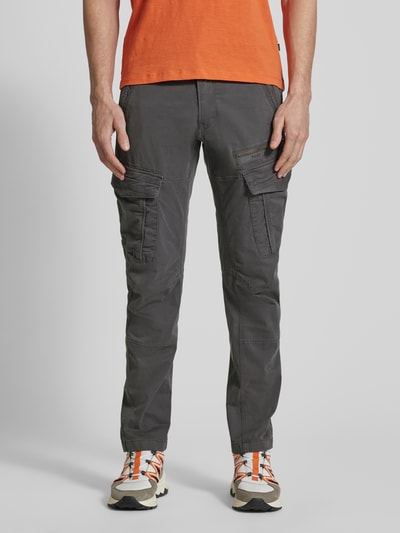 Męski model nosi Spodnie cargo z wyhaftowanym logo od PME Legend, mieszanka bawełny i elastanu, krój slim fit, kieszenie cargo, szerokość w rozmiarze 32/32: 44 cm, długość wewnętrzna nogawki: 77 cm, kolor ciemnoszary, widok całej sylwetki z przodu.