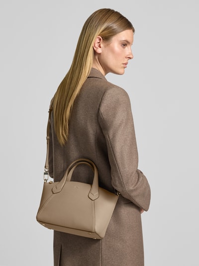Vrouwenmodel draagt schoudertas uit echt rundleer model 'Lenah' van BOSS in taupe, zachte textuur, dames schoudertas, rugaanzicht