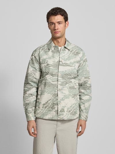 Männermodel trägt Regular Fit Hemdjacke mit Rumpftunnelzug Modell 'LELDON' von BOSS Orange, Camouflage-Muster, Ganzkörperansicht von vorne.