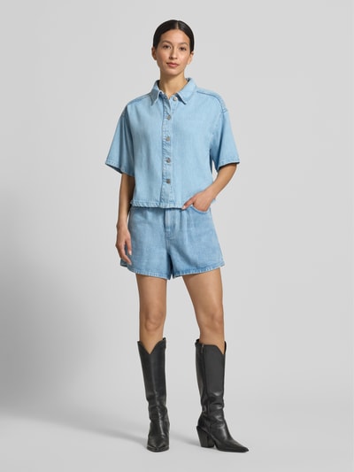 Frauenmodel trägt Straight Fit Shorts aus reinem Lyocell Modell 'Saphina' von MSCH Copenhagen in Denim-Optik mit Eingriffstaschen, Ganzkörperansicht von vorne.