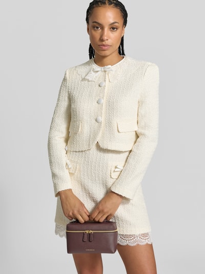 Frauenmodel trägt Henkeltasche aus echtem Leder mit Innenfach von Victoria Beckham, unifarbener matter Look mit Struktur und Logo-Prägung, Nahaufnahme Oberkörper.
