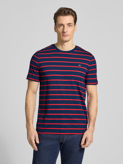 Männermodel trägt Regular Fit T-Shirt Mit Logo-Stitching von Christian Berg Men, navy mit roten Streifen, Rundhalsausschnitt, Ganzkörperansicht von vorne.
