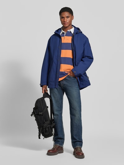 Männermodel trägt Parka mit Pattentaschen Modell 'ASKO' von Napapijri in Blau, Material-Mix, gerader Schnitt, Ganzkörperansicht von vorne.