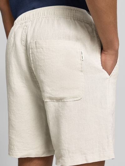 Männermodel trägt Shorts mit Eingrifftaschen Modell 'JABARI' von Samsøe Samsøe in Beige, reine Baumwolle, elastischer Bund, Ganzkörperansicht Rückansicht.