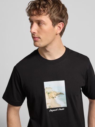 Männermodel trägt schwarzes T-Shirt mit Rundhalsausschnitt Modell 'JORNORREBRO' von Jack & Jones, Print vorne, reine Baumwolle, Nahaufnahme Oberkörper.