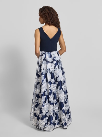 Frauenmodel trägt Abendkleid mit rückseitigem V-Ausschnitt von Christian Berg Cocktail in Blau mit floralem Muster, Material-Mix mit Stretch-Anteil, Taillierter Schnitt, Maxikleid, Rückseitiger V-Ausschnitt, Rückseitiger Reißverschluss, Rückenlänge bei Größe 36: 130 cm, Brustweite bei Größe 36: 47 cm, Ganzkörperansicht Rückansicht.