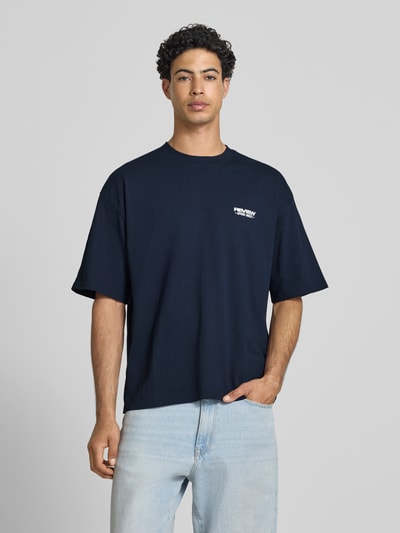 Männermodel trägt blaues Herren T-Shirt mit Rundhalsausschnitt und Logo-Print von REVIEW aus reiner Baumwolle, Modern Fit, Ganzkörperansicht von vorne.