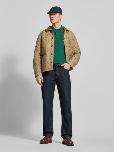 Męski model nosi Regular Fit Poloshirt aus reiner Baumwolle von Polo Ralph Lauren, efekt: jednolity kolor, krój regular fit, wyhaftowany motyw, kołnierzyk polo, dekolt w serek, krótka listwa guzikowa, krótki rękaw z prążkowanym wykończeniem, wykończenie z rozcięciami po bokach, asymetryczny, wykończenie: pika, materiał: bawełna, całopostaciowy widok z przodu.