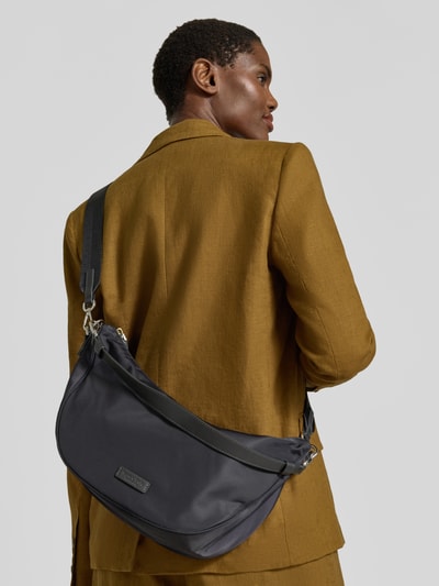 Frauenmodel trägt Umhängetasche mit abnehmbaren Schulterriemen von Marc O'Polo in Schwarz, unifarbene Optik mit Logo-Applikation, Ganzkörperansicht Rückansicht.