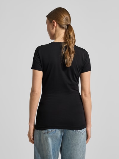 Frauenmodel trägt Slim Fit T-Shirt mit Ziersteinbesatz von Guess in Schwarz, aus elastischem Baumwoll-Mix, ganzkörperansicht Rückansicht.