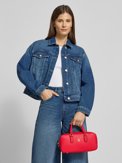 Frauenmodel trägt Umhängetasche mit abnehmbarem Schulterriemen von Tommy Hilfiger, unifarbene rote Lederoptik, Ganzkörperansicht von vorne.
