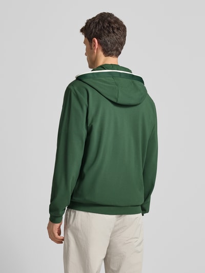Męski model nosi Sweatjacke mit Logo und Zweiwege-Reißverschluss od EA7 Emporio Armani, kolor zielony, kaptur, widok całej sylwetki z tyłu. Viskozowa mieszanka z dodatkiem stretchu, regular fit, kieszenie boczne, długość tyłu i rękawów 68 cm dla rozmiaru M.