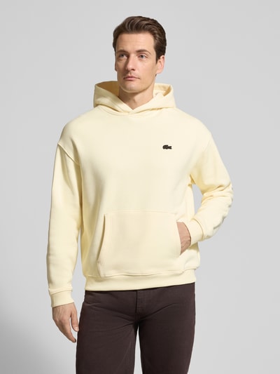 Männermodel trägt Regular Fit Hoodie aus reiner Baumwolle von Lacoste, efekt: jednolity kolor, naszywka z logo, kaptur, długi rękaw, zakończenia prążkowane, kieszeń kangurka, dzianina dresowa, bawełna, Ganzkörperansicht von vorne.