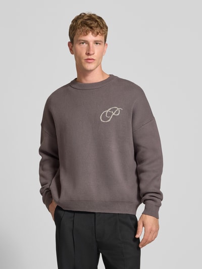 Mannelijk model draagt Relaxed Fit Strickpullover aus reiner Baumwolle van PROHIBITED in taupe, labelstitching, ribboorden, Puur katoen, relaxed fit, losse pasvorm, ruglengte maat M 64 cm, mouwlengte maat M 59 cm, Ganzkörperansicht van voren.