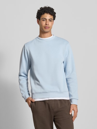 Męski model nosi Sweatshirt mit gerippten Abschlüssen Modell 'BRADLEY' od Jack & Jones, jasnoniebieski, bawełniany materiał, krój regular fit, okrągły dekolt, faktura gładka, długość tyłu w rozmiarze M 67 cm, długość rękawa w rozmiarze M 65 cm, widok przód – ujęcie górnej części sylwetki.
