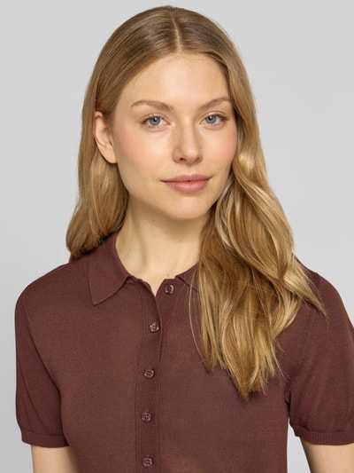 Frauenmodel trägt Strickshirt mit Polokragen und kurzer Knopfleiste Modell 'TENCYP' von Mango in Braun, moderne Passform, Nahaufnahme Oberkörper.