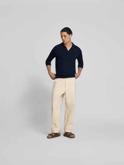 Männermodel trägt Slim Fit Poloshirt aus Woll-Mix von Filippa K in Strick-Optik, dunkelblau, langärmelig, Ganzkörperansicht von vorne.