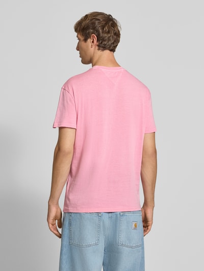Männermodel trägt Regular Fit T-Shirt aus reiner Baumwolle von Tommy Jeans in Rosa, glatte Oberfläche, Ganzkörperansicht Rückansicht.