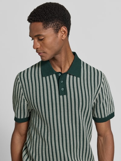 Męski model nosi Regular Fit Poloshirt in Strick-Optik von MCNEAL z bawełny, kołnierzykiem polo, krótki rękaw, imitacja dzianiny, ujęcie z przodu, zbliżenie na górną część ciała.