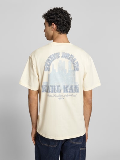 Männermodel trägt Oversized T-Shirt mit rückseitigem Print von KARL KANI aus reiner Baumwolle mit Label-Stitching, Ganzkörperansicht Rückansicht.
