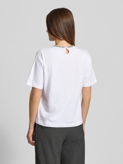 Kobieta modelka nosi białe T-shirt z bawełny JOOP!, model 'Thei', luźny krój, detal z logo przy dekolcie, widok całej sylwetki z tyłu.