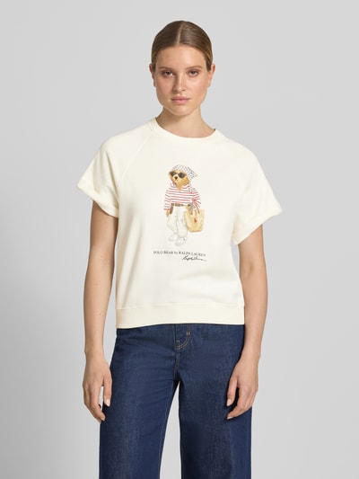 Kobiece modelka nosi Regular Fit Sweatshirt mit Polo Bear Print od Polo Ralph Lauren, efekt: jednolity kolor, krój: krój regular fit, aplikacja: nadruk polo bear, kształt kołnierza: crew neck, dekolt: okrągły dekolt, rękaw: raglanowe rękawy, zakończenie rękawów: prążkowane, wykończenie materiału: dzianina dresowa, materiał: mieszanka bawełny, widok: całe ciało z przodu.