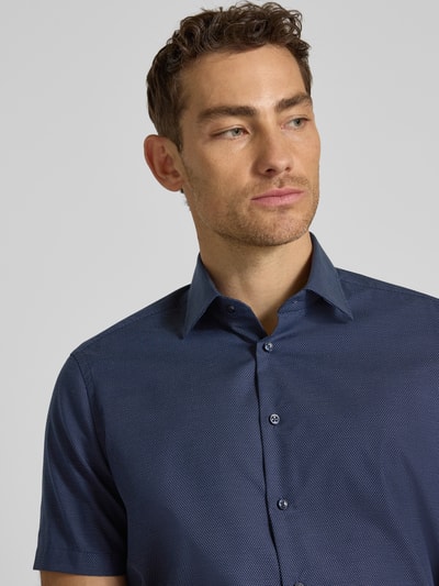 Mannelijk model draagt Regular Fit Business-Hemd aus Baumwolle met Kentkraag van Christian Berg Men, donkerblauw met fijne structuur, korte mouwen, halfhoge knopenlijst, pure katoen, regular fit, halve mouw, voorkant close-up.