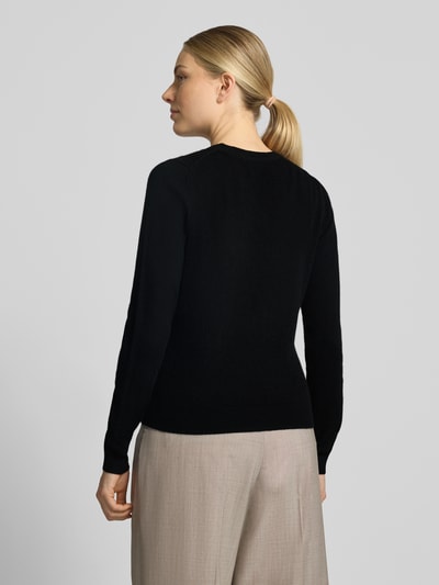 Modelka kobieca nosi czarny sweter z kaszmiru Slim Fit od Christian Berg Woman, taliowany krój, elastyczne wykończenia, długość tyłu 54 cm, długość rękawów 65 cm, widok całej sylwetki z tyłu.