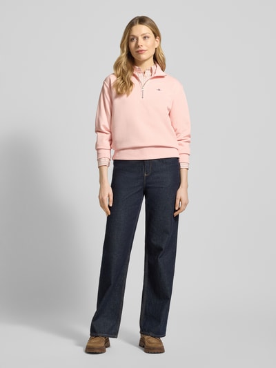 Frauenmodel trägt Sweatshirt mit Baumwoll-Anteil von Gant in Rosa mit Troyer-Kragen, Lockerer-Schnitt, Label-Stitching, gerippte Abschlüsse, Ganzkörperansicht von vorne.