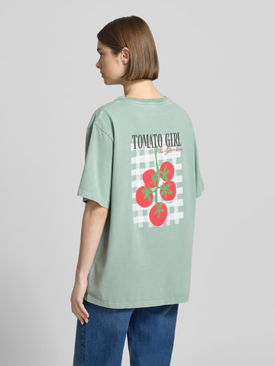 Frauenmodel trägt Oversized T-Shirt mit Label-Stitching von OH APRIL aus Reine Baumwolle, Rückenlänge 69 cm, Ganzkörperansicht Rückansicht.