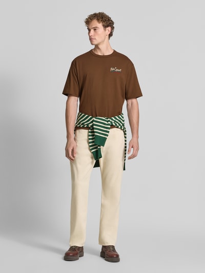 Męski model nosi Relaxed Fit T-Shirt aus reiner Baumwolle od Polo Ralph Lauren, brązowy, kremowe spodnie, pełny widok z przodu