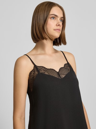 Frauenmodel trägt schwarzes, ärmelloses Loose Fit Blusentop mit Spitzenbesatz, feine Struktur, von PIECES, Nahaufnahme Oberkörper.